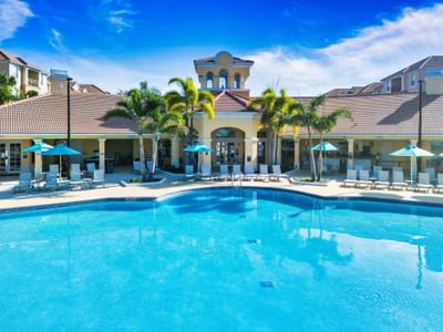 Pool with chairs and umbrellas in front of resort building at Vista Cay Resort By Millenium