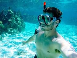 A man in snorkel gear taking a selfie underwater near Bayside Inn Key Largo
