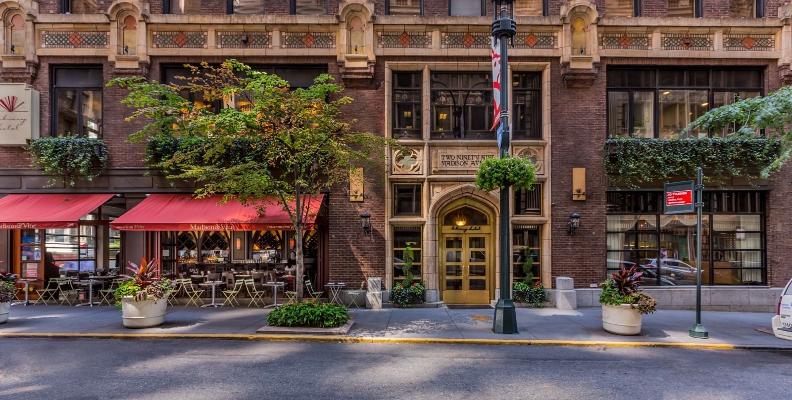 Vue extérieure du Library Hotel avec auvents au-dessus du café-terrasse et porte en arc