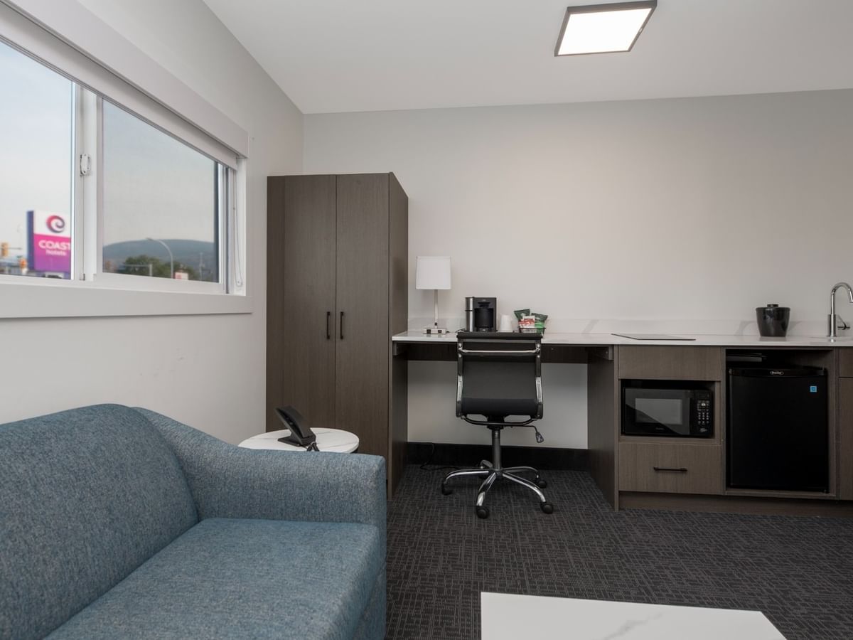 Modern room suite with couch, desk, chair, microwave, and mini-fridge.