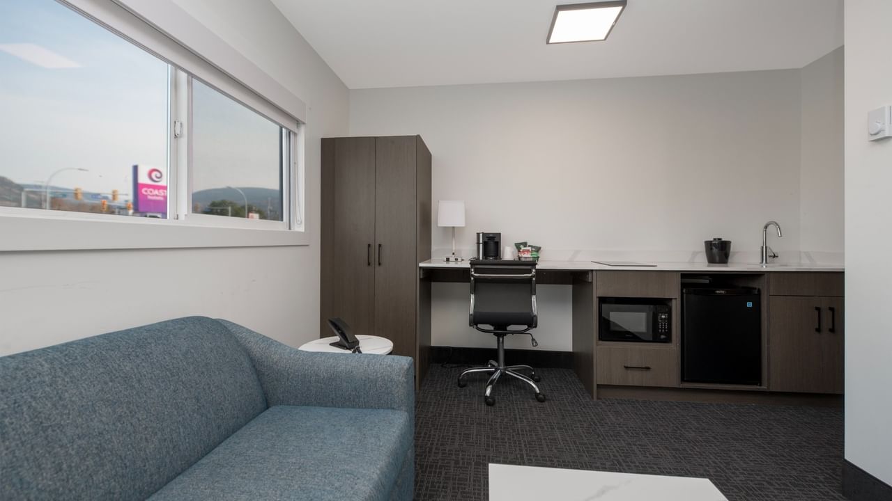 Modern room suite with couch, desk, chair, microwave, and mini-fridge.