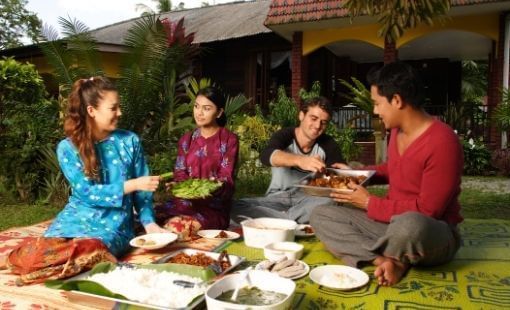 Group of friends sitting outdoors on a mat & sharing a meal at Sunway Hotel Big Box