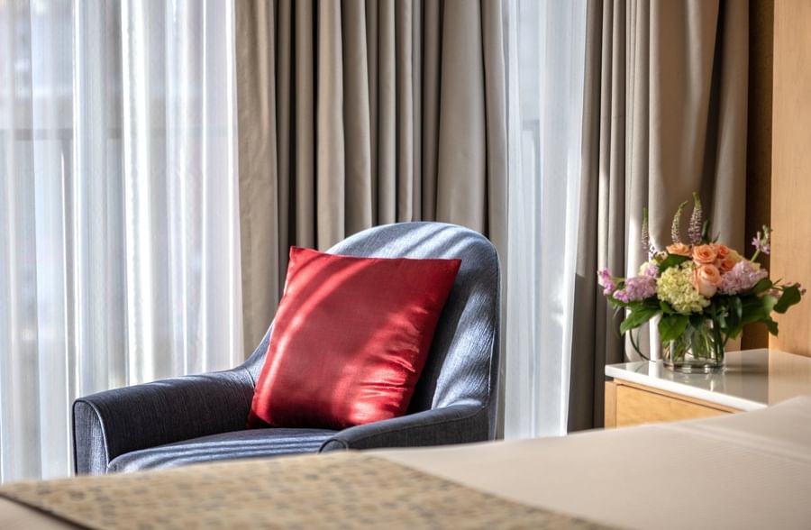 Comfortable chair with red pillow and floral arrangement on a table in a Deluxe Room at Warwick Seattle