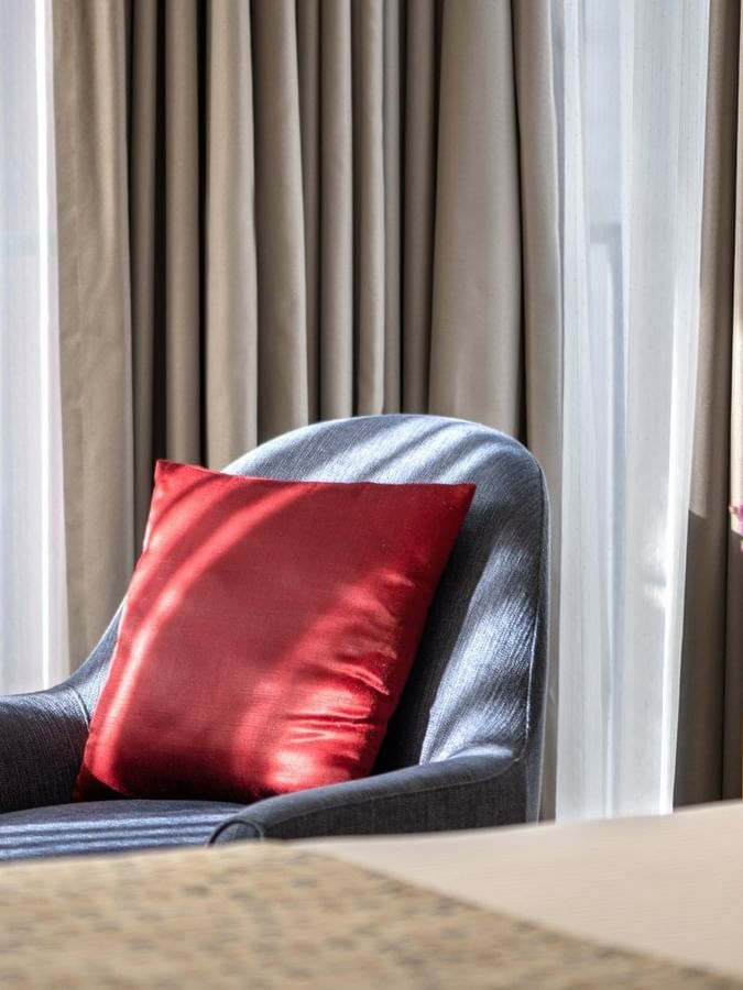 Comfortable chair with red pillow and floral arrangement on a table in a Deluxe Room at Warwick Seattle