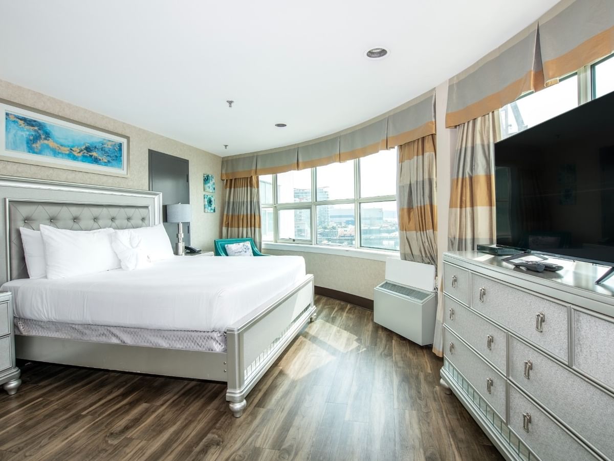 Coast Carrie Cates Penthouse Suite with large bed, dressers, flat-screen TV, large windows at Coast Lonsdale Quay Hotel