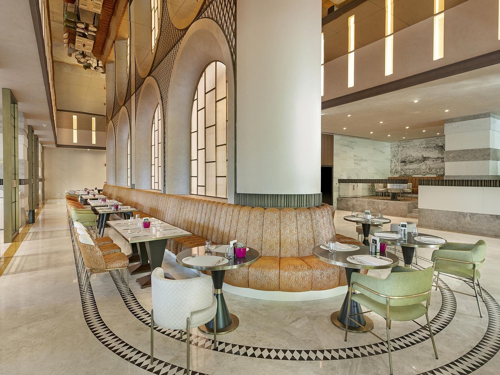 Dining area with arched windows & a curved bench in Mare Main Restaurant at Cullinan Belek