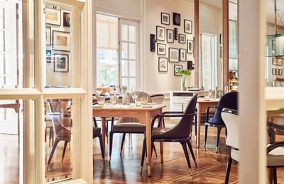 Opera Restaurant with wooden tables, stylish chairs, and framed art on the walls at Park Hyatt Saigon