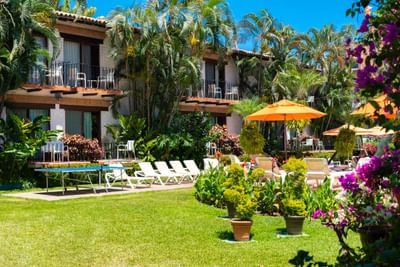 Resort with balconies, sun loungers, umbrellas, and lush greenery in a serene outdoor setting.