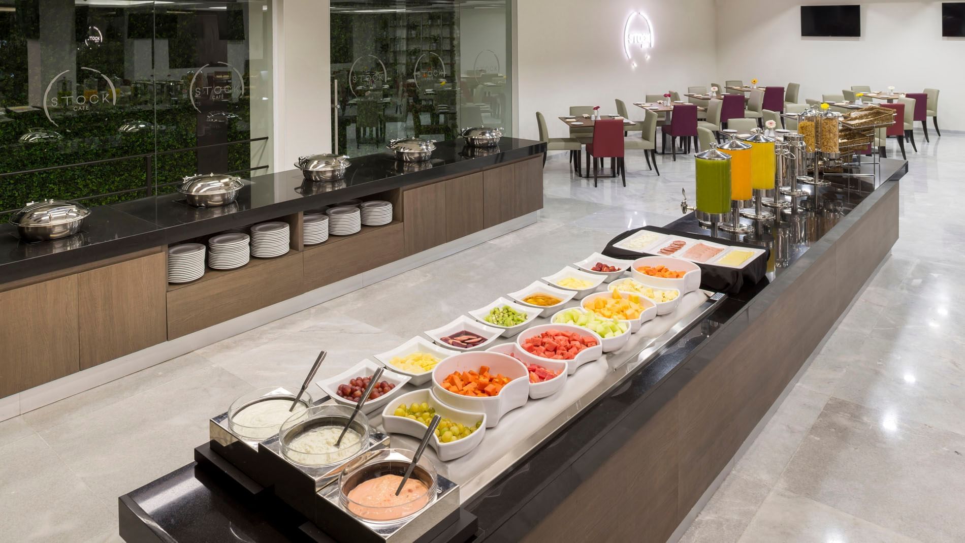 Fresh breakfast buffet served in Stock Cafe with various fruits, juices, and hot dishes in a modern cafe at Real Inn Celaya