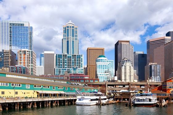 White ferries docked by a colorful pier building under a cloudy sky near Paramount Hotel Seattle