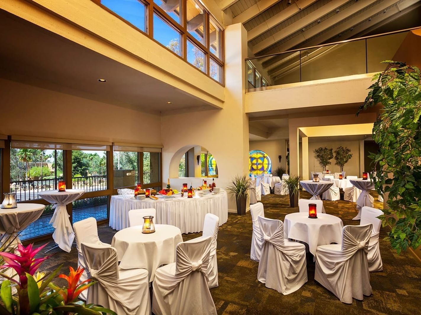 Palacio event space with white-draped tables, colorful centerpieces, and natural light at Hilton Phoenix at the Peak
