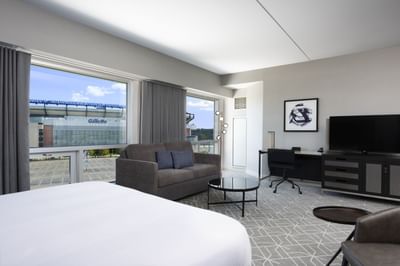 room with bed, small sofa, desk and dresser with television