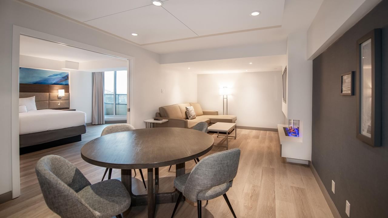 Living room with couch, table, and dining set in Coast Premium King One Bedroom Suite at Coast Bastion Hotel in Nanaimo.