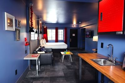 Studio King room featuring a blue color scheme, a black couch, a wooden table, and a cozy bed at The Gaythering