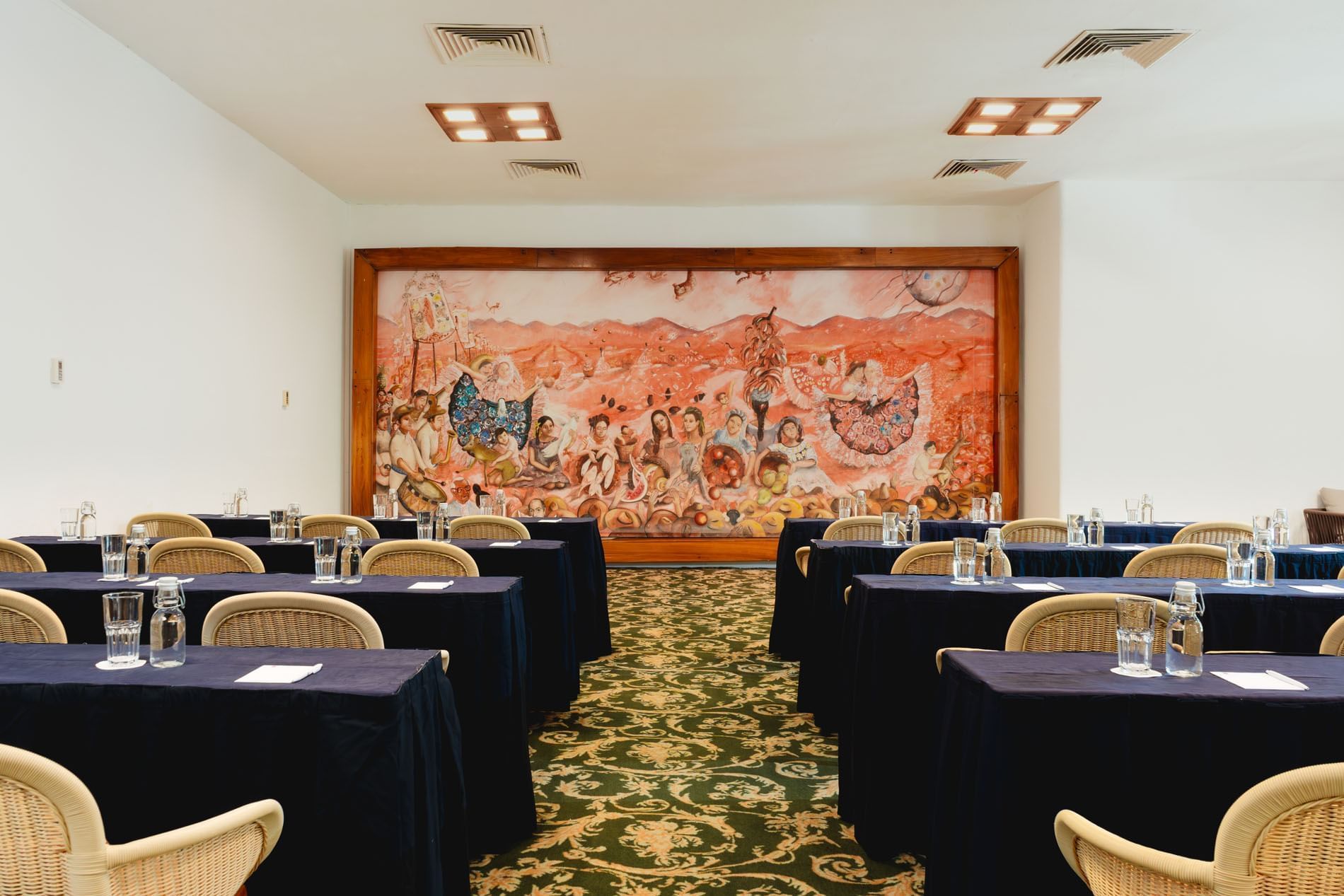 Classroom set-up in Indato II with carpeted floors and a vibrant mural on the wall at Camino Real Zaashila Huatulco