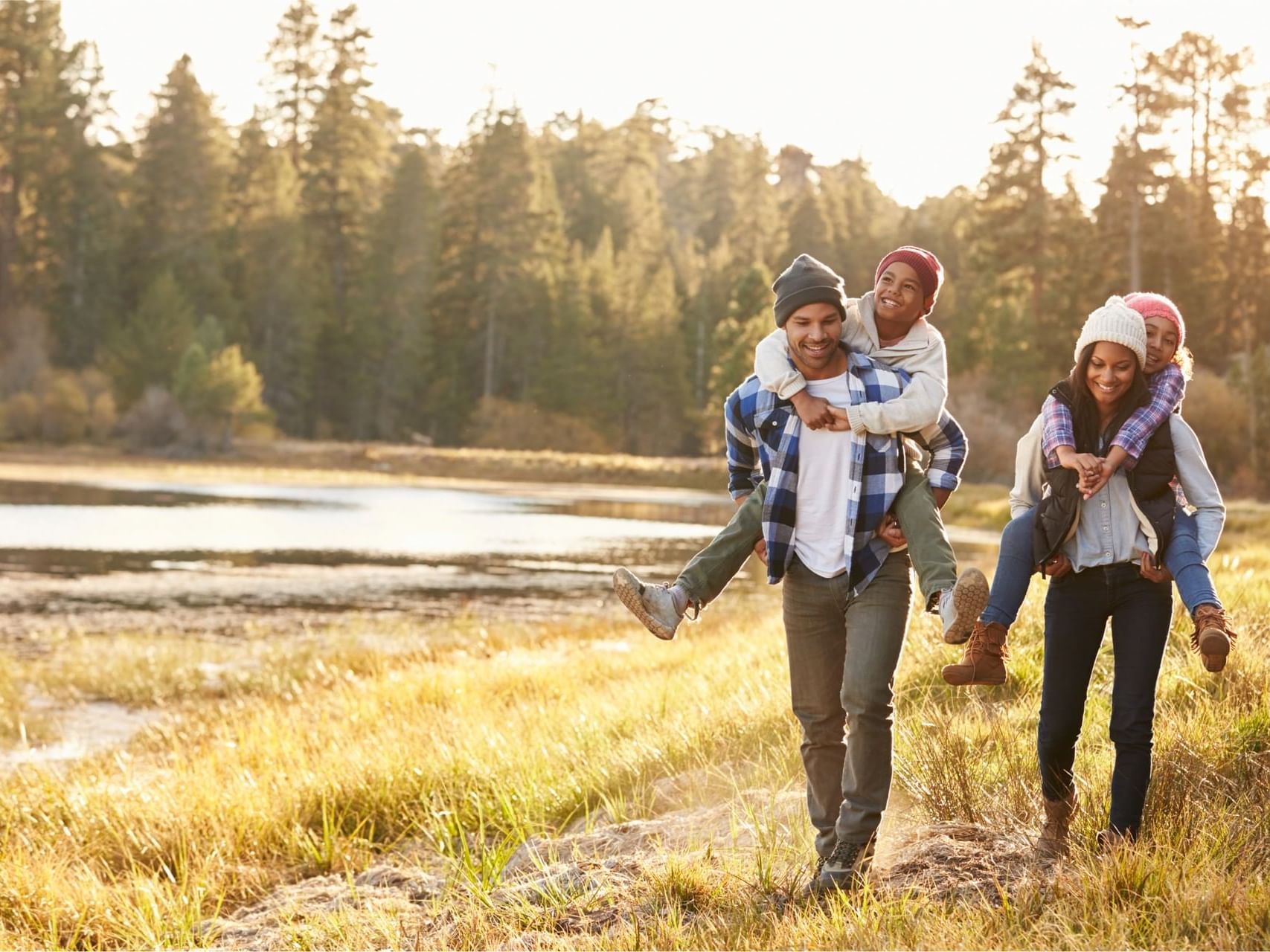 Young family is hiking outdoors in a grassy area near a body of water and a forest near Fall Creek Marina & Campground