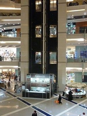 Wide interior view of Abraj Al-Bait Mall with glass elevators and boutiques near Saja by Warwick Makkah