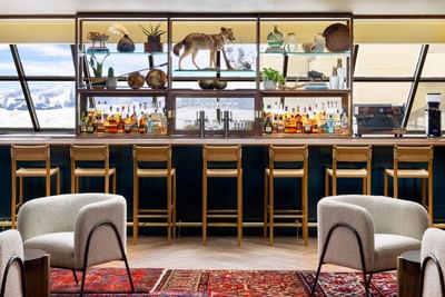 Billy Barr seating area with stools, a wolf figurine, and bottles at Elevation Resort Spa