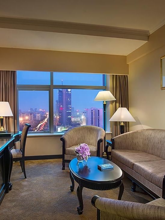 TV lounge with sofa and work desk by the window in the Business Suite at Celebrity International Grand Hotel