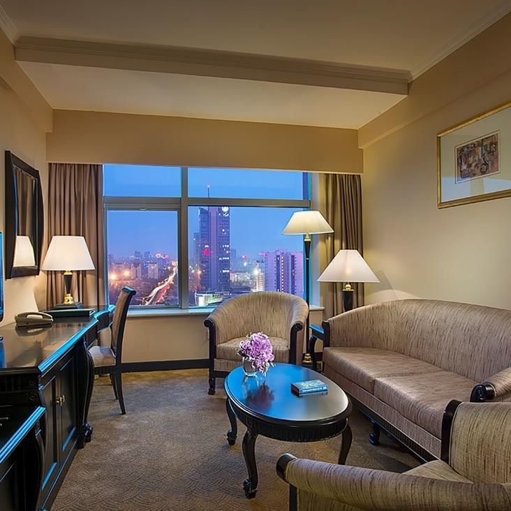 TV lounge with sofa and work desk by the window in the Business Suite at Celebrity International Grand Hotel