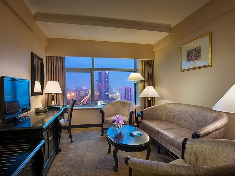 Living area with cozy chairs and a TV in Business Suite at Celebrity International Grand Hotel