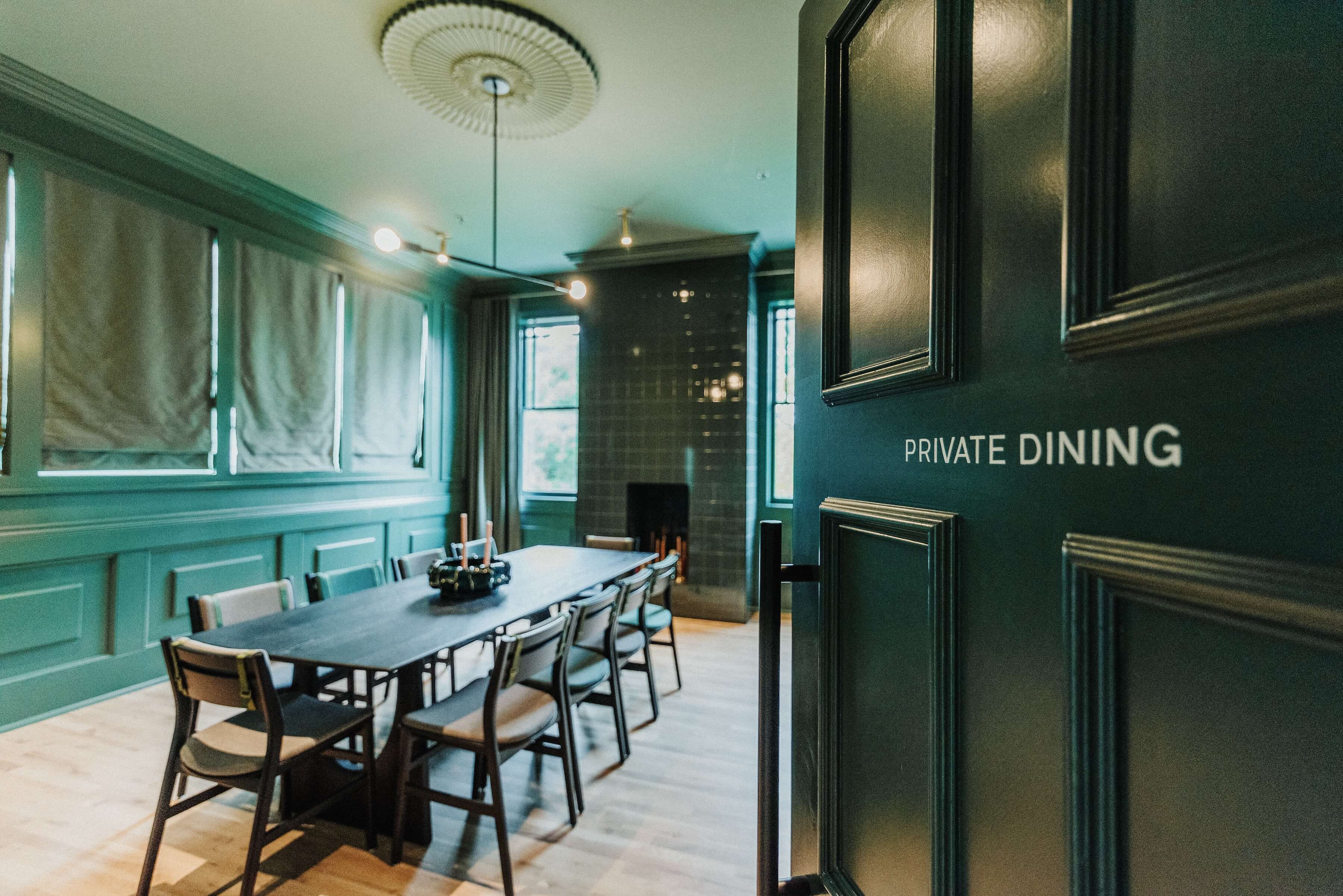 A door opening to a private event room with a tiled fireplace, tv, and a table that seats ten guests.