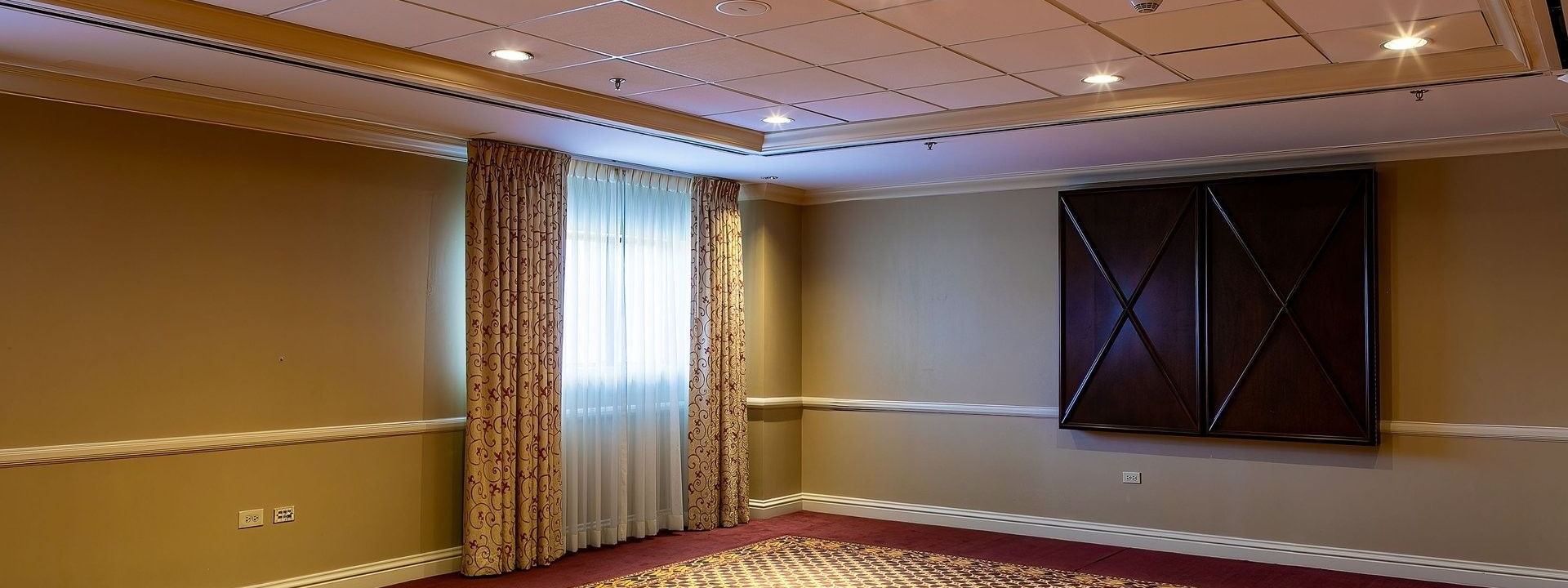 Empty event room with patterned carpet by tan walls under a grid ceiling in Capitol I/II/III at Warwick Denver