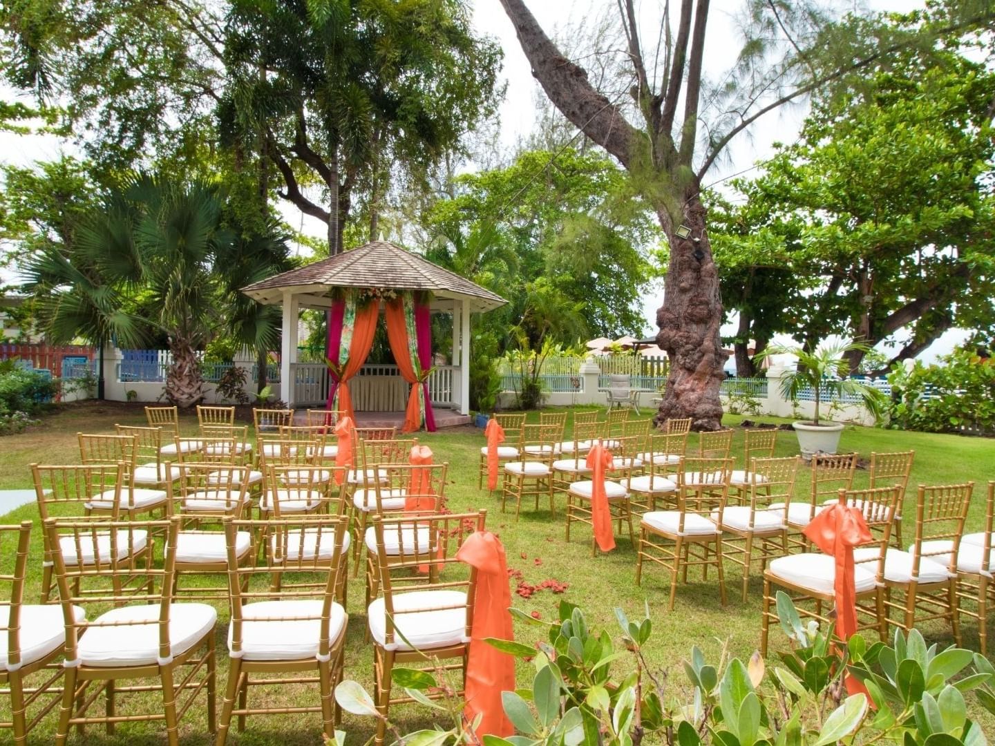 Chairs arranged on a lawn with a gazebo and orange decorations at Savannah Beach Hotel.