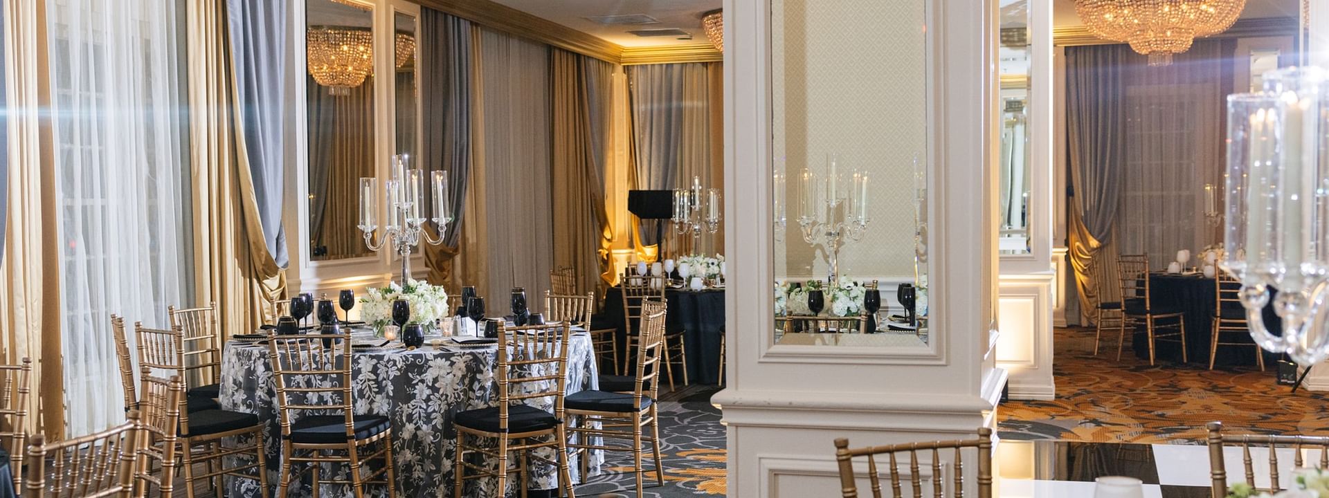 Round table with a silver cloth by gold chairs under a chandelier in Crystal Ballroom at Warwick Melrose Dallas