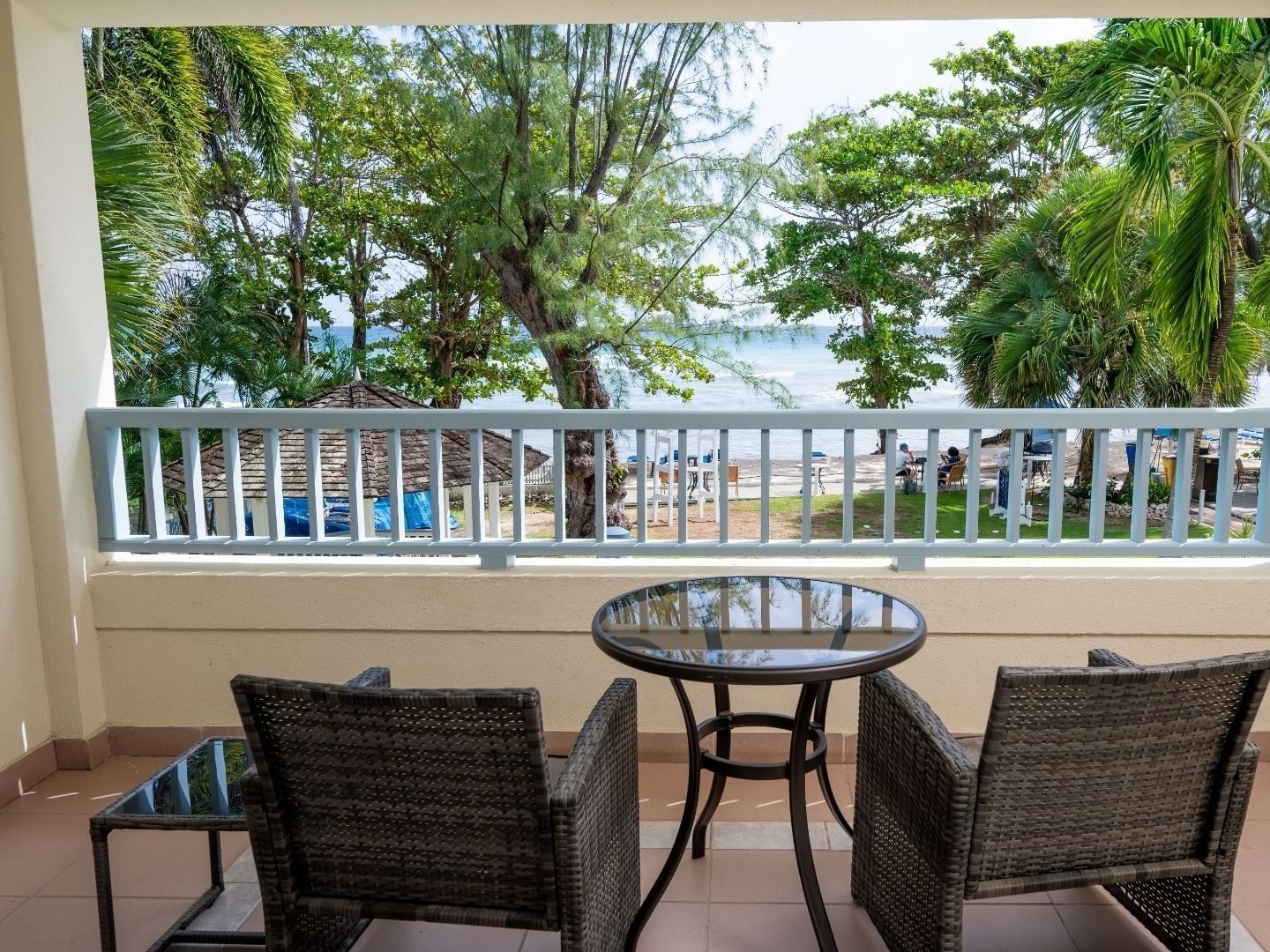 Two wicker chairs and a glass table on a balcony overlooking the beach at Savannah Beach Hotel.
