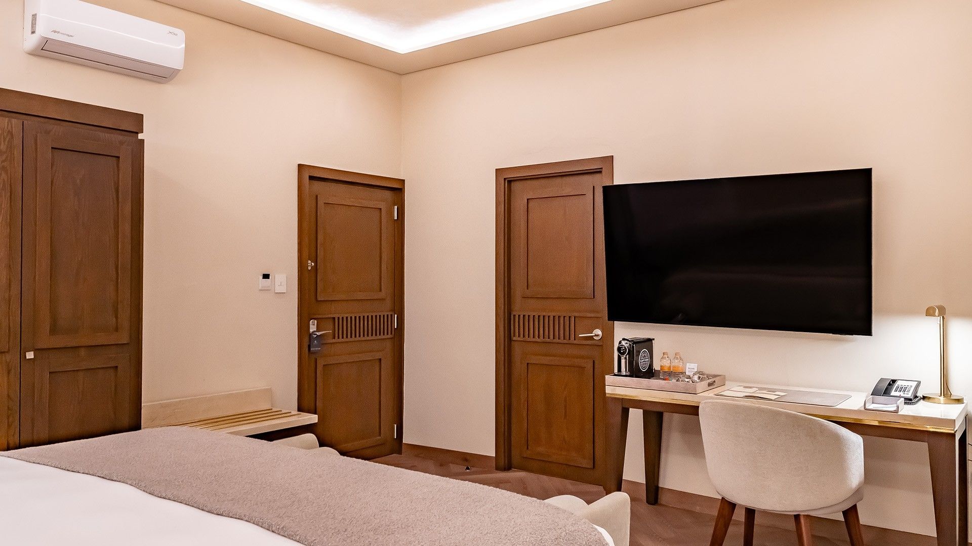 King Real room detail showing wood doors, a coffee machine on a desk, and a large TV at Quinta Real Puebla