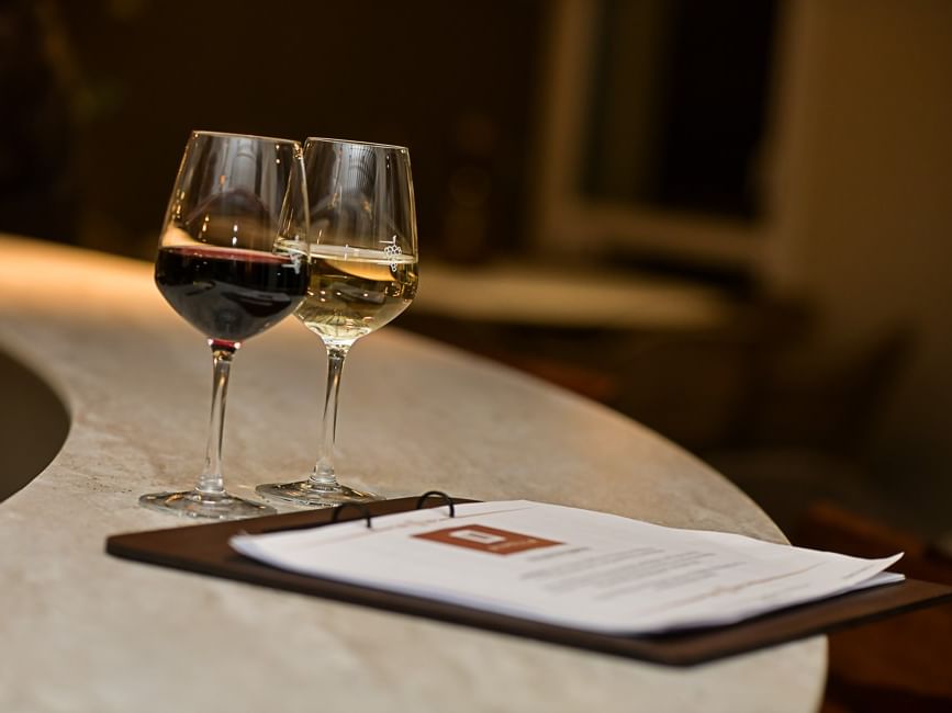 Deux verres de vin et un menu sur une table à Hôtel Rivella.