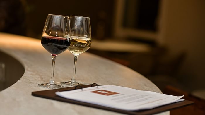 Deux verres de vin et un menu sur une table à Hôtel Rivella.