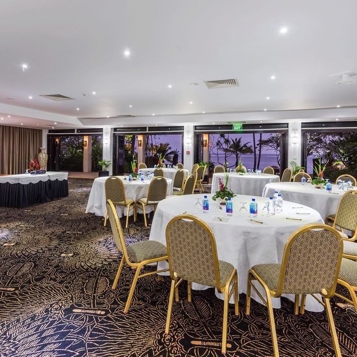 Coral Coast Conference Centre with round tables and chairs by glass doors at Warwick Fiji Resort and Spa
