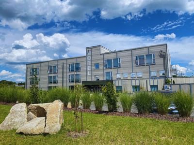 Avaneo Hotel Marktredwitz with signage surrounded by green grass, plants, and rocks,one of the sustainable hotels