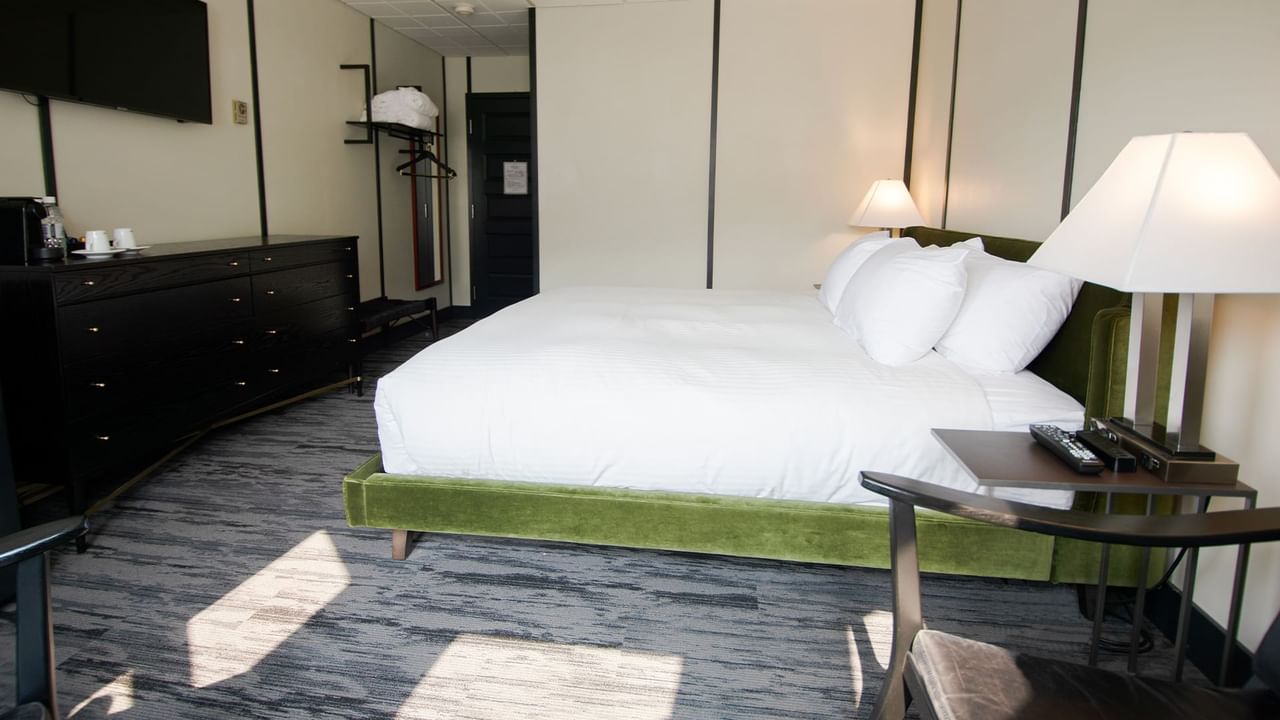 Hotel room with king bed, lamp, night stand, premium coffee, TV, chair, and window