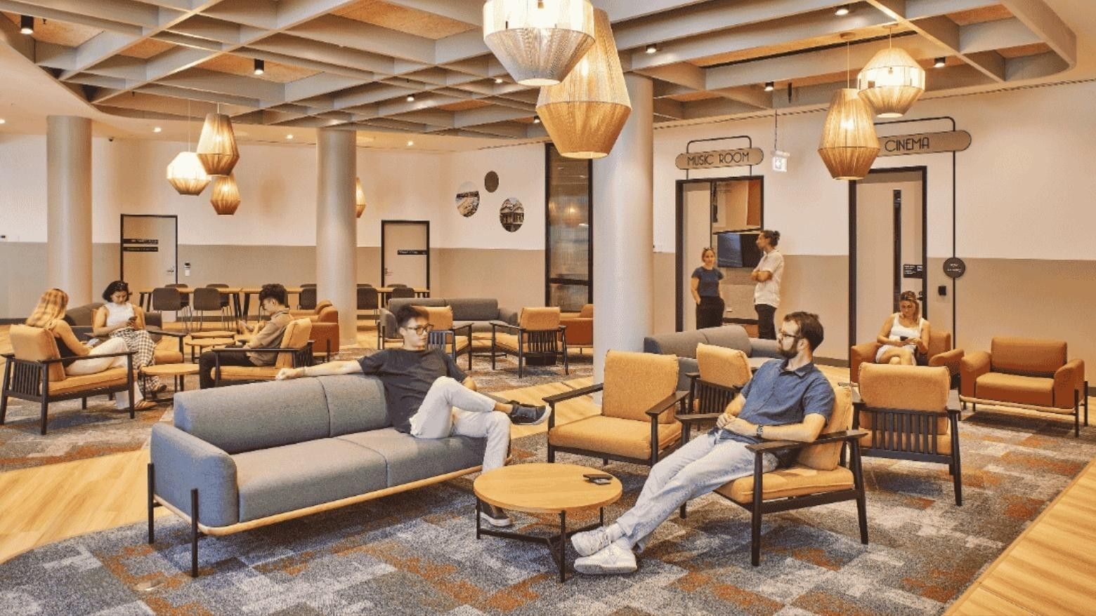 People seated on furniture in a lounge area with a music room and cinema.