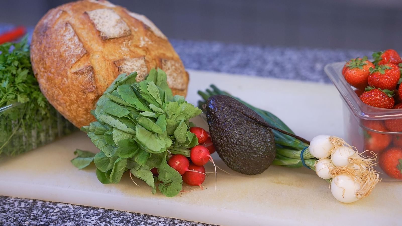 Fresh radish, avocado, and bread loaf placed by spring onions on a board at Warwick Grand Place Brussels