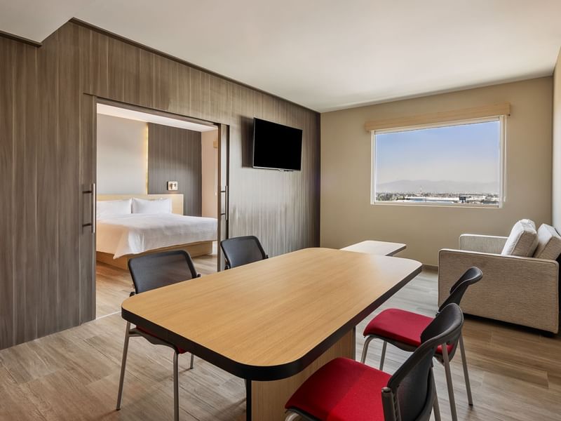 Wooden table with chairs and a bed in Junior Suite King at Gamma Hotels