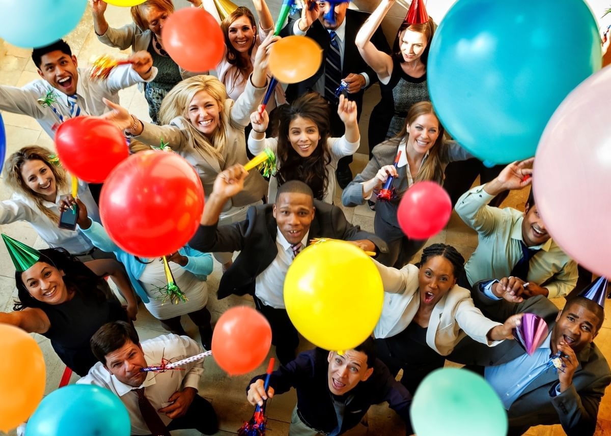 A joyful team celebrating, looking up and posing for a photo with colorful balloons at Novotel Sydney Olympic Park