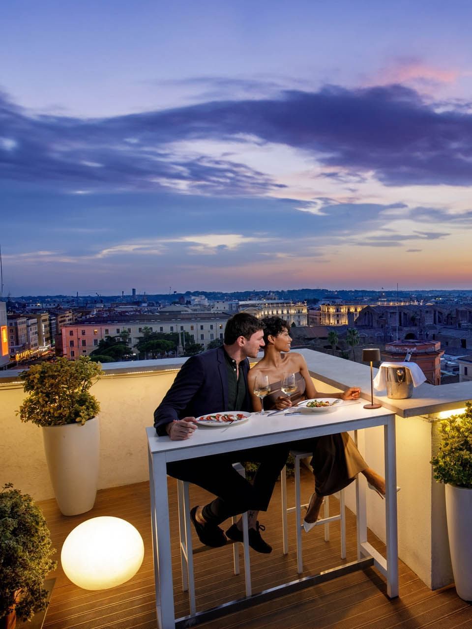 Couple enjoys a romantic dinner on Terrazza Cielo rooftop, with a vibrant city sunset at The Independent