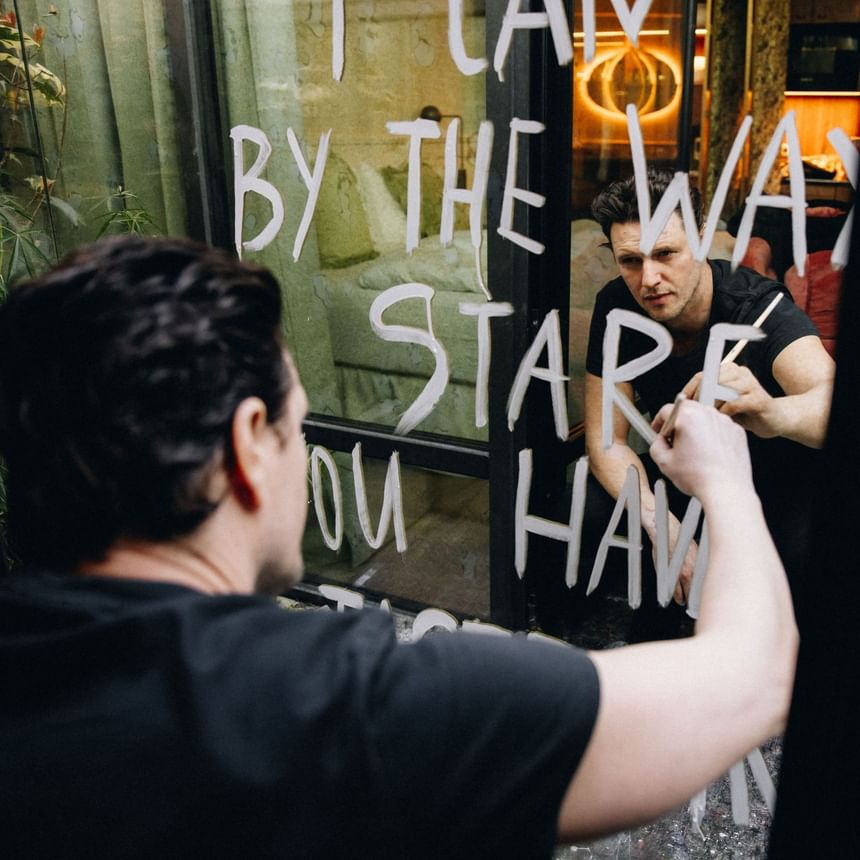 Man writing on the glass with reflective white paint in Art Deluxe Room at Hotel Motto Vienna