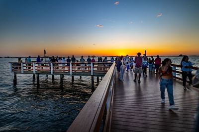 Crowded pier with people enjoying the view over shimmering water near The J Hotel, featuring things to do in Dunedin, FL
