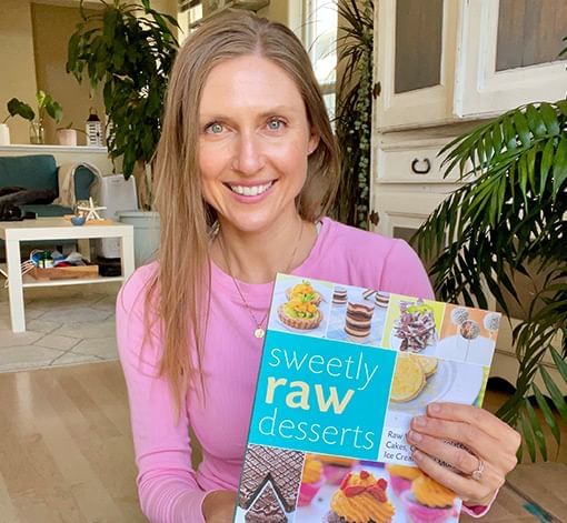 Chef Heather Pace holding her Sweet Raw Desserts book