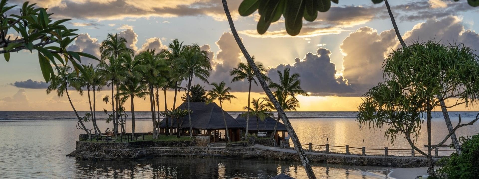 Wicked Walu by a stone walkway under a golden sunset near palm trees at Warwick Fiji Resort and Spa