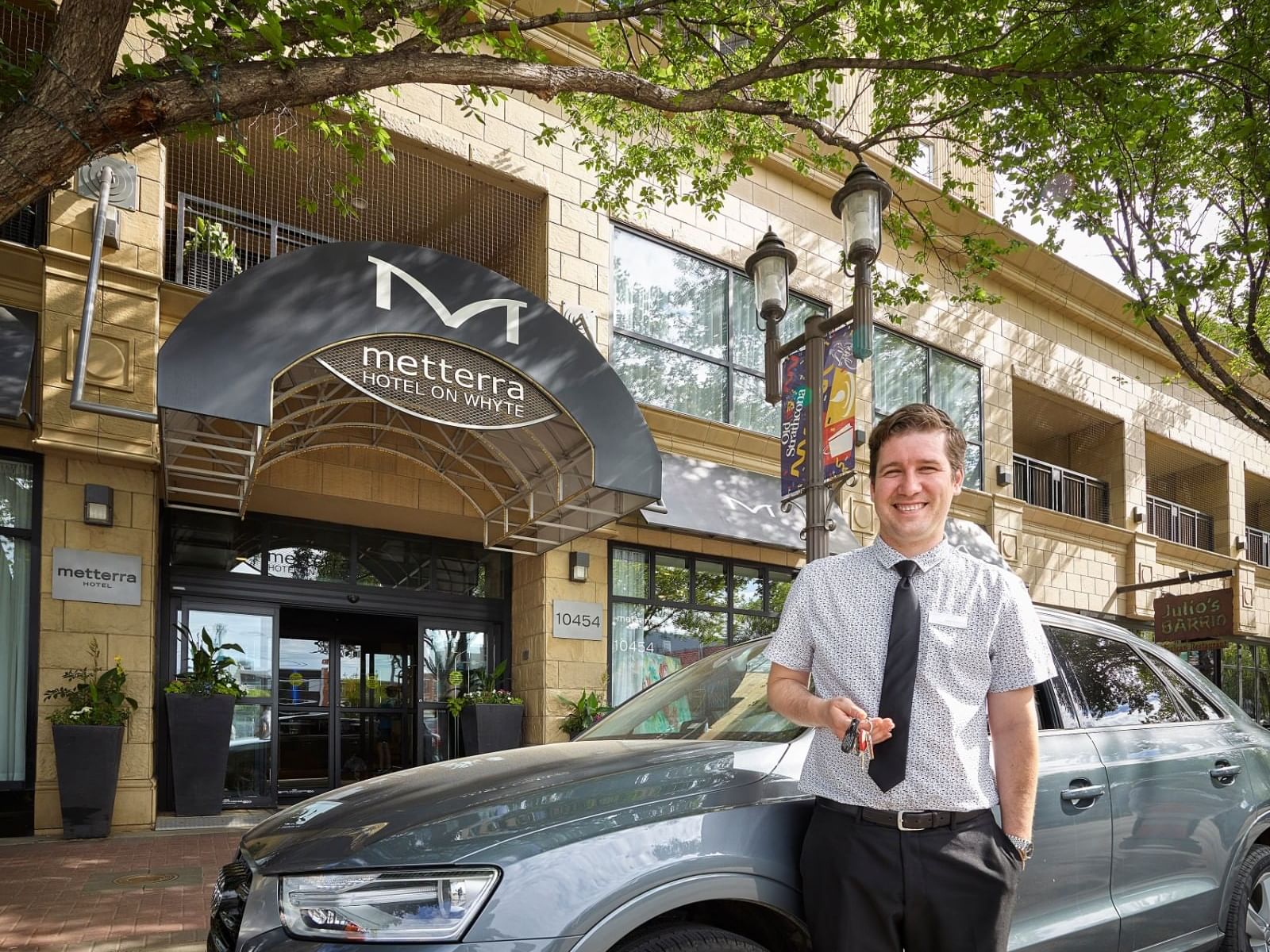 A valet standing next to a car in front of Metterra Hotel on Whyte