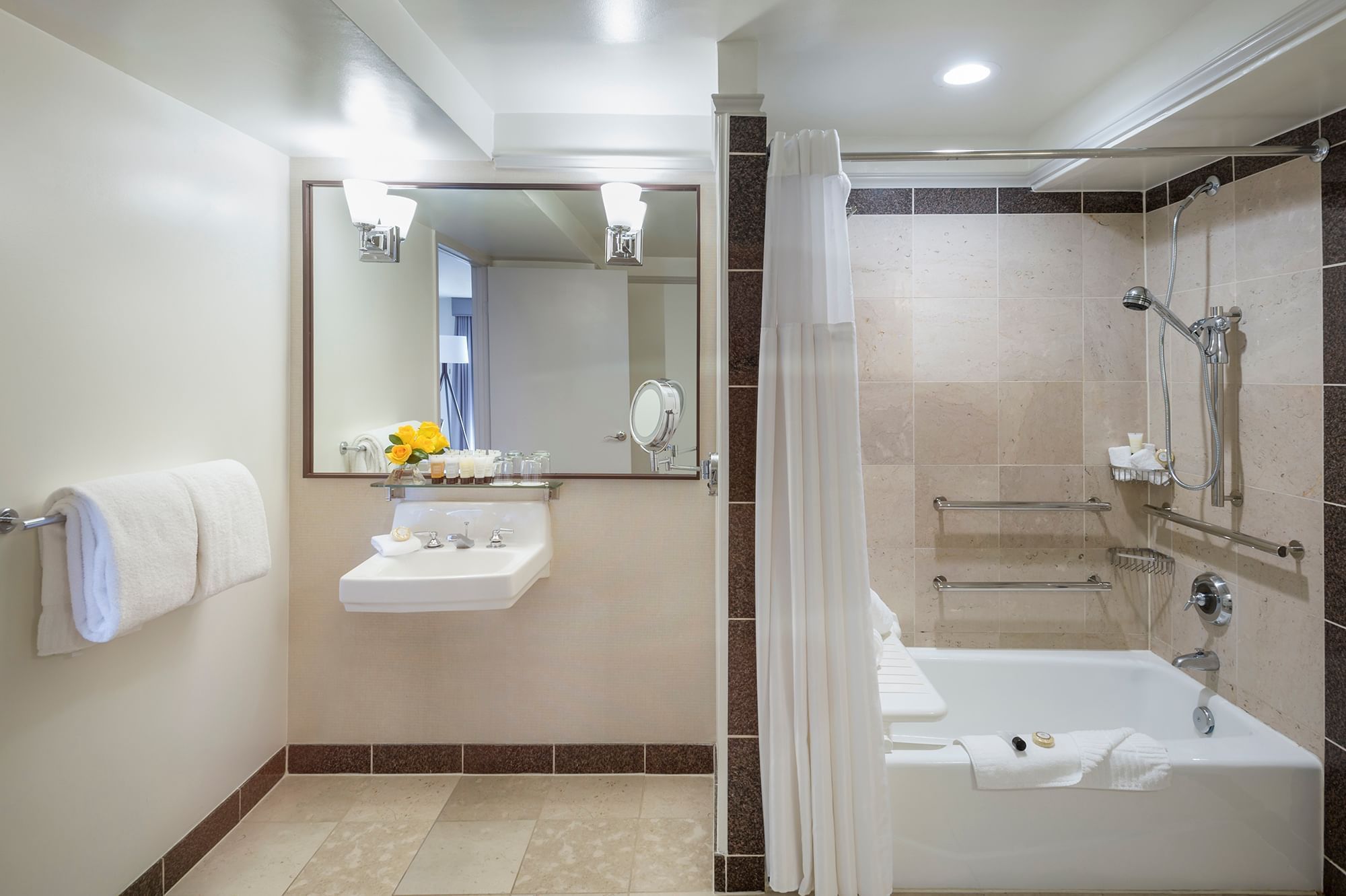 A clean and well-appointed bathroom with a bathtub, shower curtain, grab bars, and handheld showerhead.