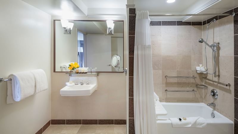 Bathtub and sink with mirror in Accessible Deluxe Room at Warwick Denver