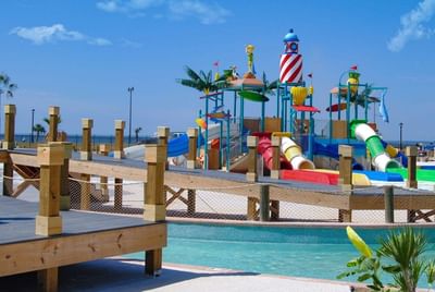 Water park with multiple slides and a lighthouse-themed structure, viewed from a wooden deck at Centennial Plaza Resort