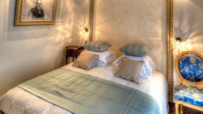 Chambre élégante avec lit, couverture bleue, oreillers et chaise à l'Hôtel Villa Aultia.